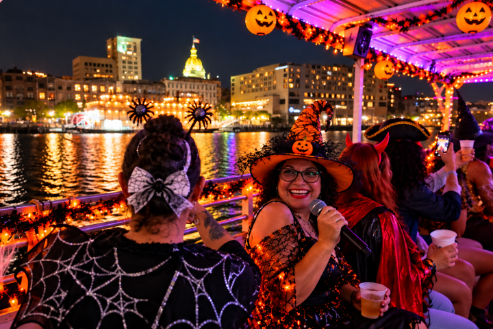 People in Halloween costumes enjoying a decorated boat ride at night.