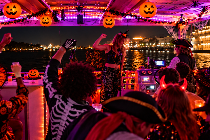 Halloween party on a boat, people in costumes, pumpkin decorations.